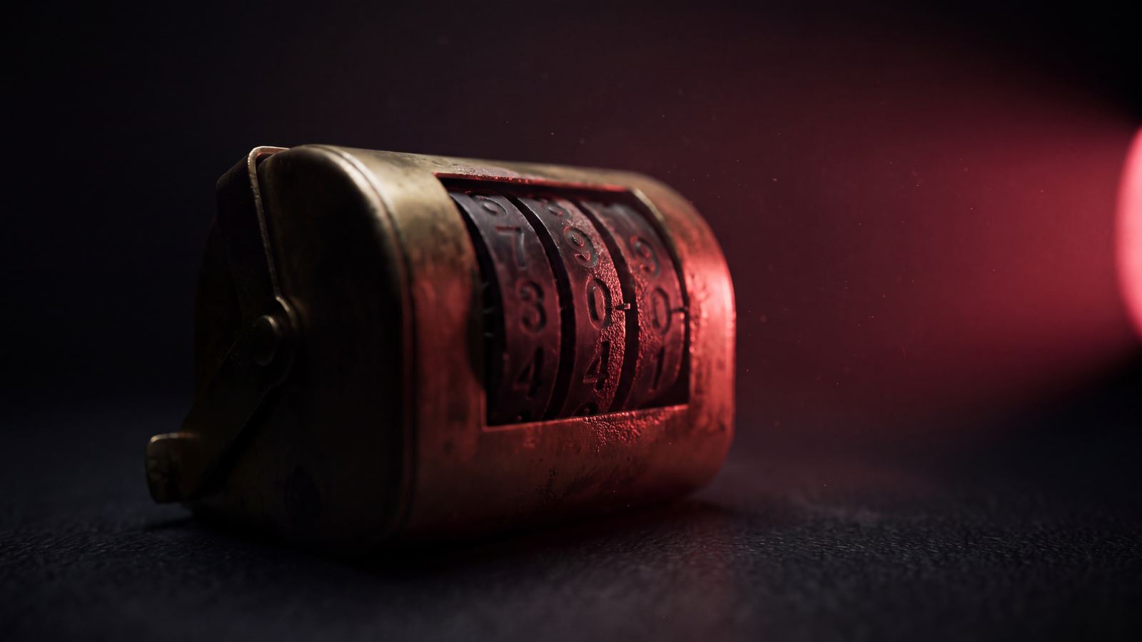 A worn brass tally counter seen from the side, its numbered wheels part-turned, crimson light raking across them against black.