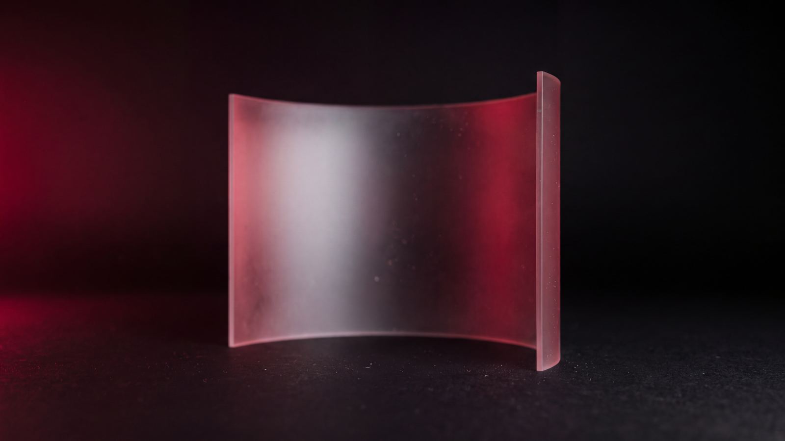 A curved sheet of frosted acrylic lit from behind, a cool white core blooming outward into crimson.
